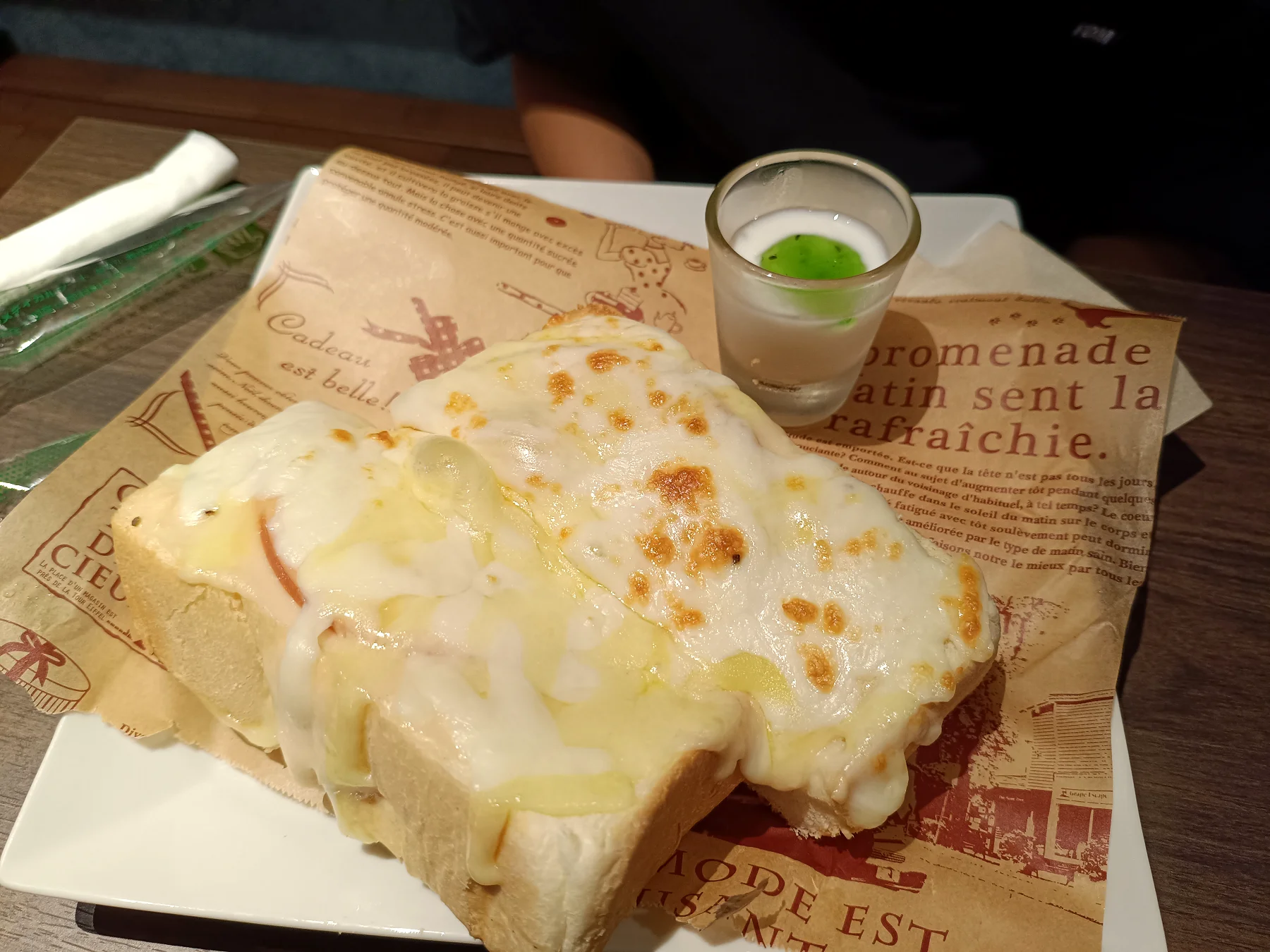 チーズがたっぷりのったトーストの写真。小さなデザートグラス付き
